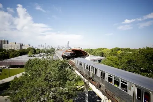 A green line train enters the tube above MTCC.